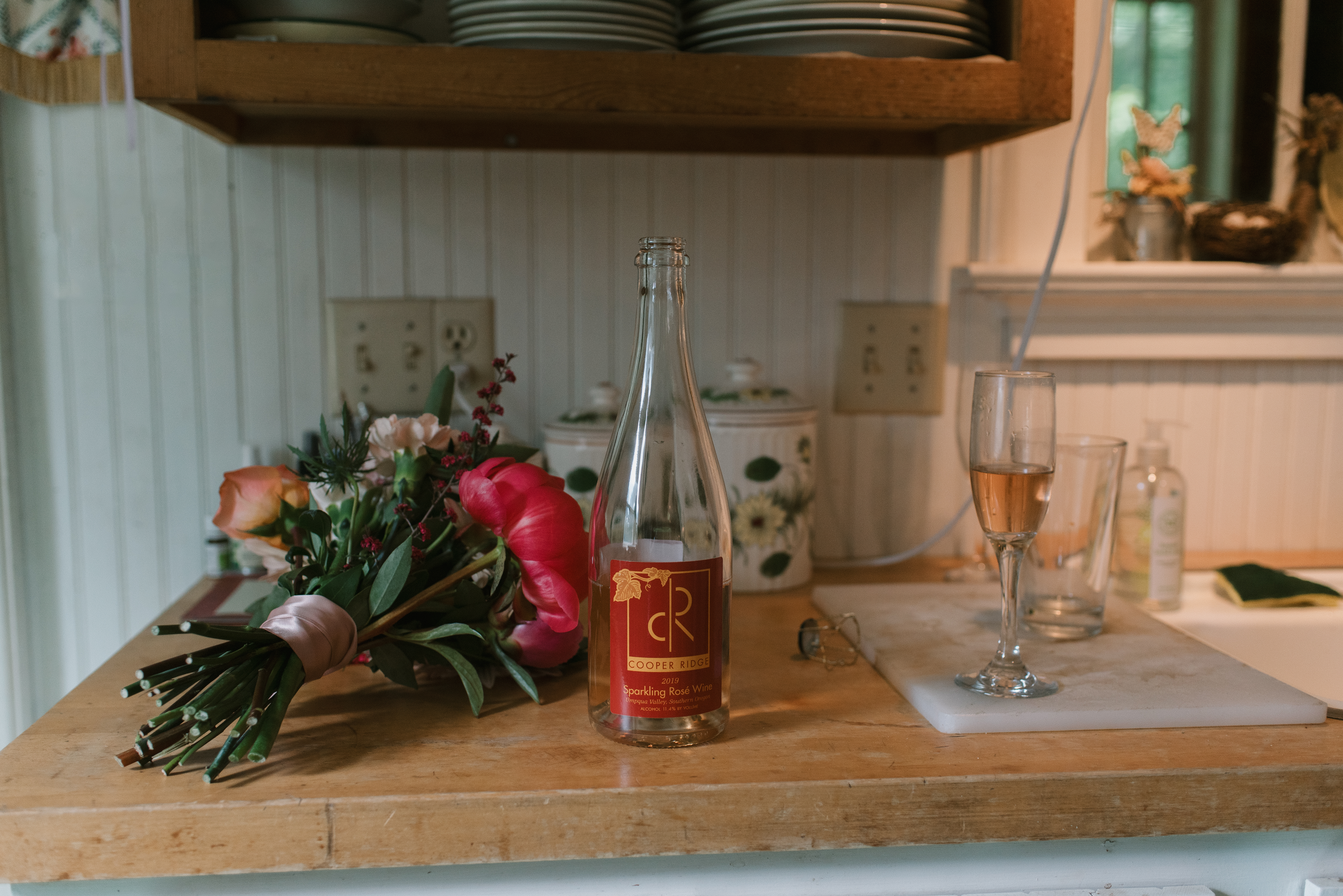 empty wine bottle next to bridesmaids bouquets