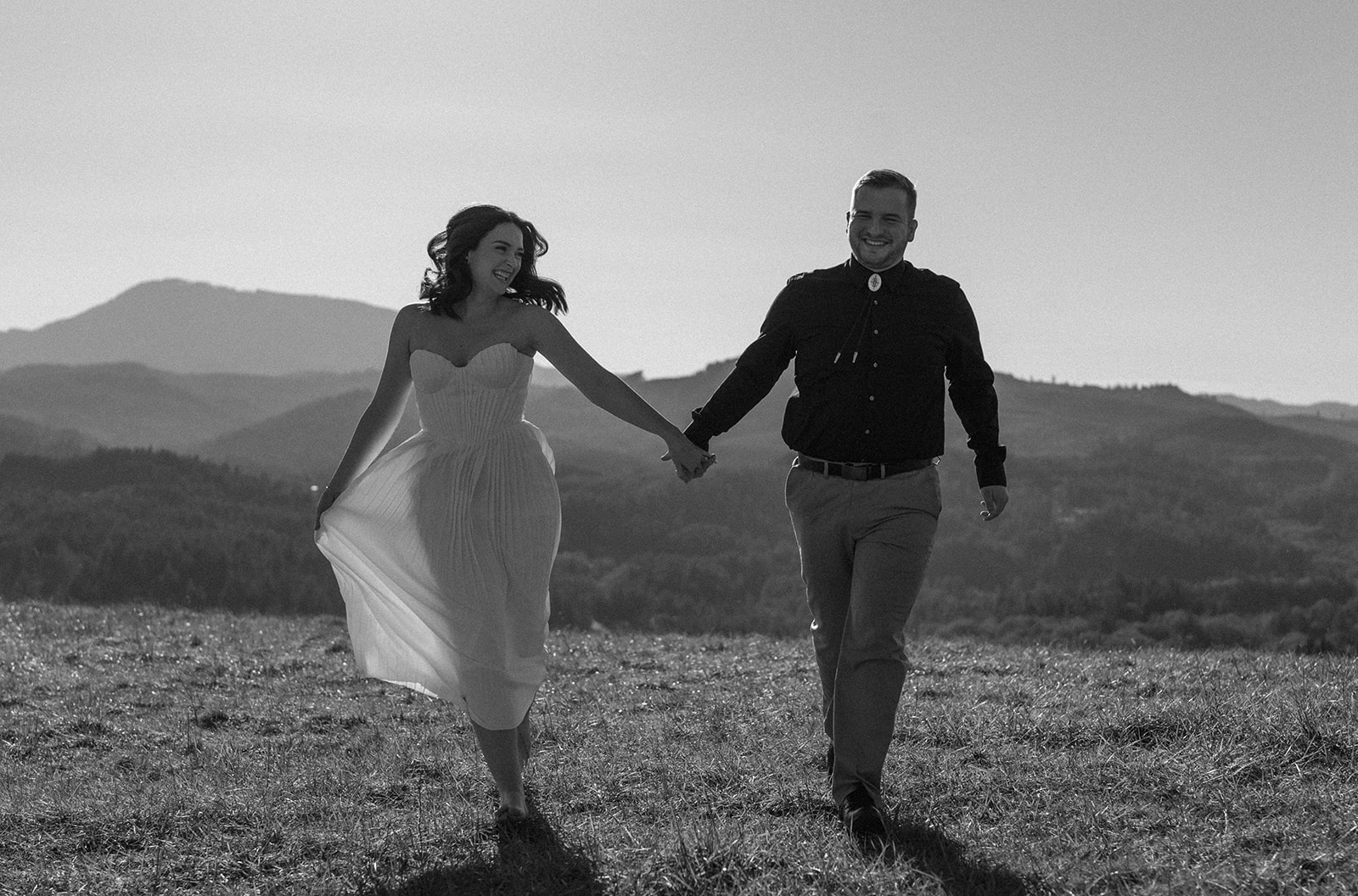 black and white photo of couple frolicking in a field