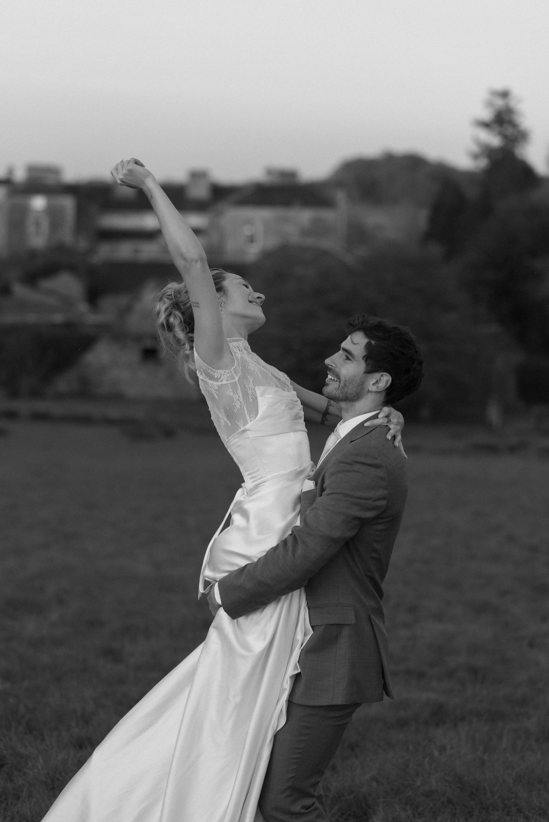 black and white photo of couple being carefree in a sheep field in ireland