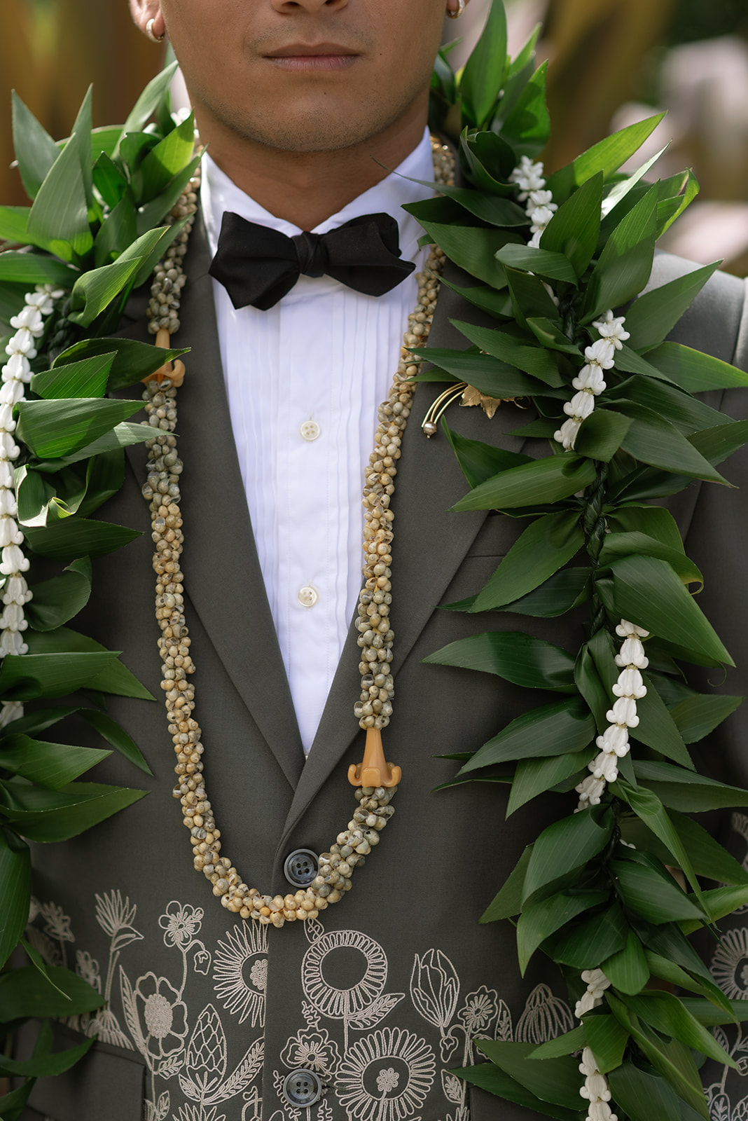 personal photo of groom's embroidered wedding suit and hawaiian leis 